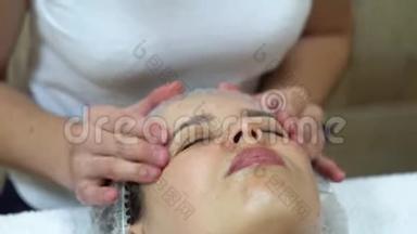 按摩治疗师正在对客户面部进行手工按摩.. 面部美容治疗.. 水疗面部按摩